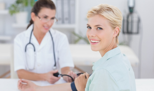 Foto: Eine Ärztin misst den Blutdruck einer jungen Frau.