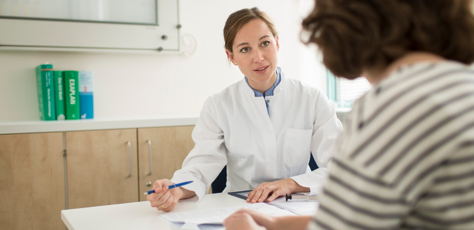 Patientenberatung (Bildquelle: Thomas Koehler/BMG) Foto: Eine Ärztin in weißem Kittel sitzt an einem Schreibtisch und erklärt einer Patientin etwas.
