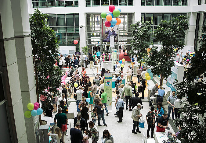 Foto: Blick vom ersten Stock aus ins Foyer, wo sich Besucher an den Ständen reihen