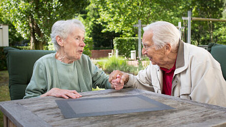 Zwei ältere Menschen halten Händchen