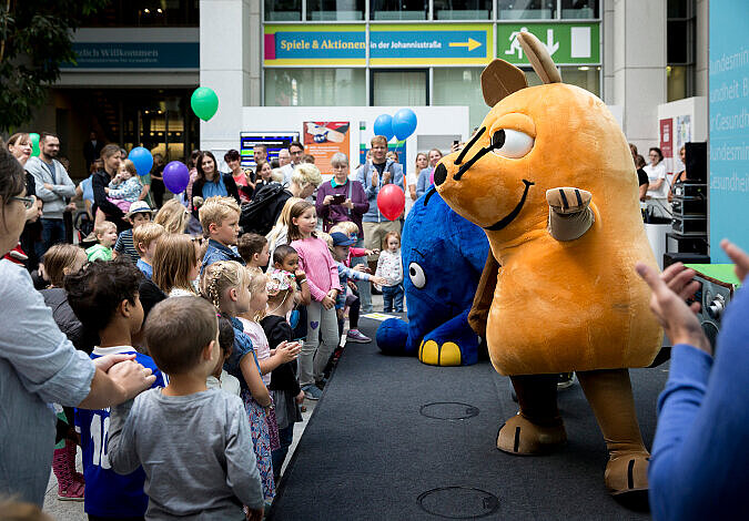 Die Maus und der Elefant tanzen vor einem großen Kinderpublikum auf der Bühne des BMG