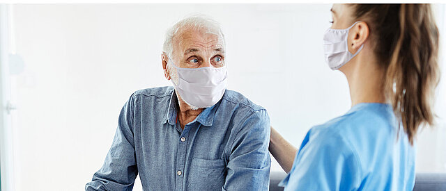 Patient und Pflegerin mit Maske