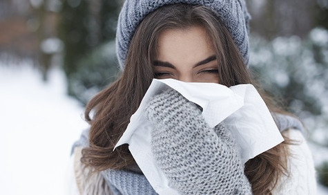 Jetzt gegen Grippe impfen (Bildquelle: gpointstudio/Shutterstock) Eine Frau mit Wollmütze und Handschuhen hält ein Taschentuch bereit, um sich die Nase zu putzen