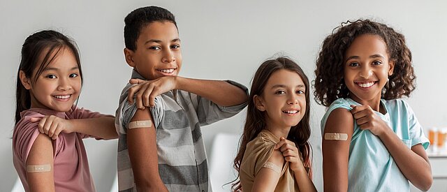 Kinder zeigen ihre Impfung am Arm
