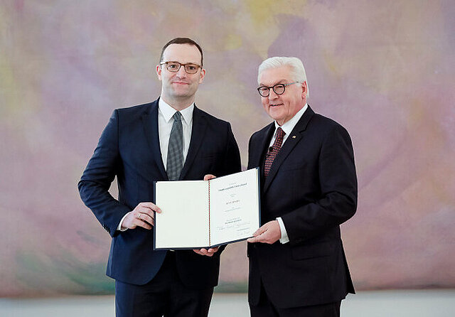 Foto: Jens Spahn und Frank-Walter Steinmeier halten gemeinsam die Ernennungsurkunde in die Kamera und lächeln