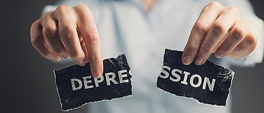Ein Mann zerreißt einen Zettel mit der Aufschrift "Depression"