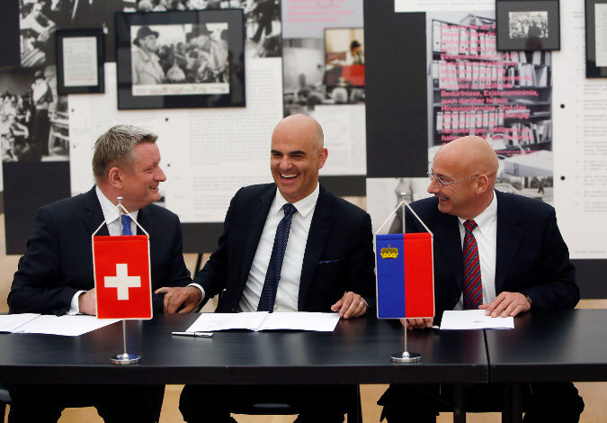 Foto: Bundesgesundheitsminister Gröhe und seine Amtskollegen aus der Schweiz und Lichtenstein sitzen miteinander scherzend am Tisch; vor ihnen liegt die Erklärung zur Unterschrift