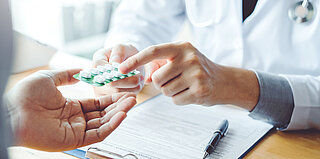 Arzt übergibt Tabletten an Patienten - Entwicklung eines KI-basierten Entscheidungsunterstützungssystems zur individualisierten Vorhersage wirksamer Antibiotikatherapien