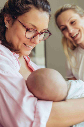 Zwei Frau lächeln ein Baby an. 