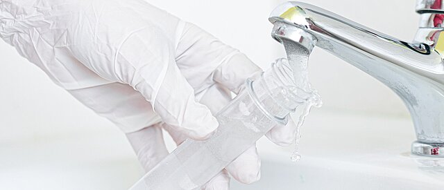 Labor-Glas wird unter Wasserhahn gefüllt