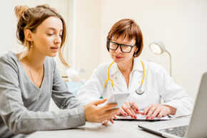 Patientin mit Smartphone in der Hand im Gespräch mit einer Ärztin