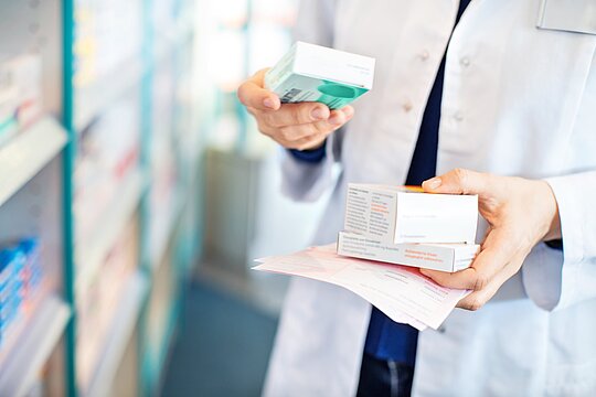 Apothekerin hält Rezept und drei Packungen Medikamente in der Hand