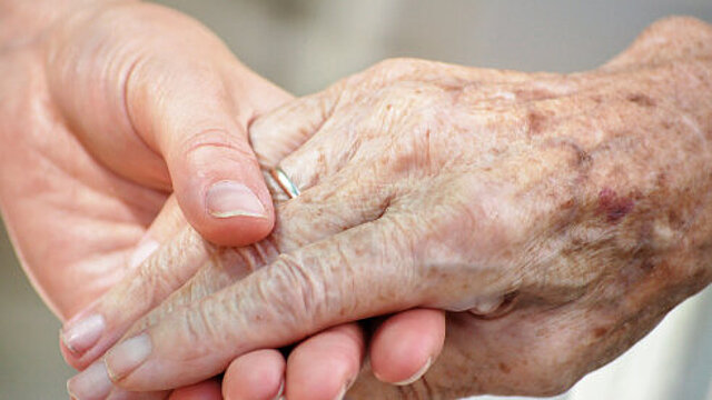 Foto: Die Hand einer jungen Frau greift die Hand einer alten Frau 