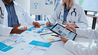 Ärzte des Gesundheitswesens und Besprechungsunterlagen mit Tablet-Daten für Geschäftsgespräche im Büro. Medizinischer Papierkram Kommunikation und Analytik Verbesserung für die Entwicklung von Medicare Unternehmen.