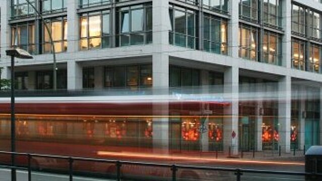 Foto: Das Dienstgebäude des Bundesgesundheitsministeriums in der Berliner Friedrichstraße; am Gebäude fährt eine Straßenbahn vorbei 