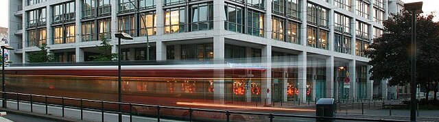 Foto: Das Dienstgebäude des Bundesgesundheitsministeriums in der Berliner Friedrichstraße; am Gebäude fährt eine Straßenbahn vorbei 