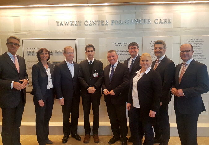 Foto: Gruppenfoto mit Minister Gröhe im Yawkey Center for Cancer Care, dessen Name in silberfarbenen Buchstaben auf der weißen Steinwand hinter der Gruppe zu lesen ist