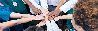  Eine Gruppe von Menschen mit unterschiedlichen Hautfarben bilden einen Kreis.