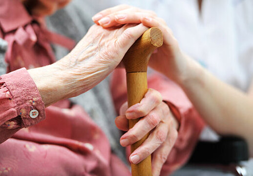 Foto: Die Hand einer jungen Frau umfasst die Hand einer alten Frau.