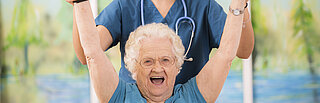 Eine Pflegerin treibt mit einer Senioren Sport.