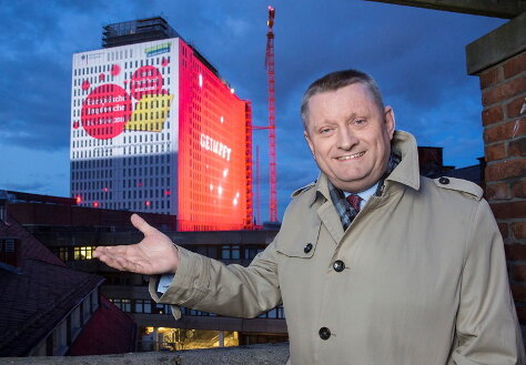 Foto: Bundesgesundheitsminister Hermann Gröhe steht vor der Projektion der symbolischen Masernpunkte auf das Bettenhochhaus der Universitätsklinik Charité.