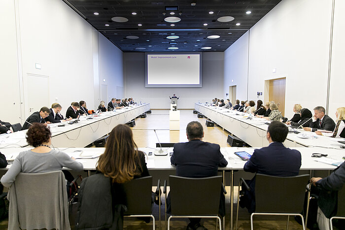 Foto: Blick in einen Workshop-Veranstaltungsraum, im Vordergrund sitzen Zuhörer mit dem Rücken zum Betrachter, aus deren Perspektive man auf die Präsentation schaut 