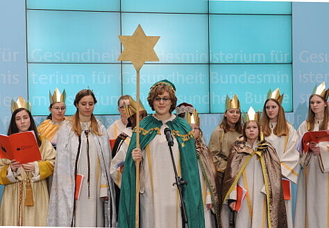 Foto: Die Sternsinger – in den Kostümen der Heilige Drei Könige – singen auf einer Bühne