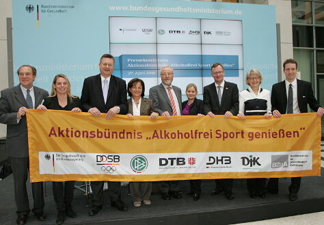 Foto: Marlene Mortler hält zusammen mit den Aktionspartnern die Bandarole des Aktionsbündnisses "Alkoholfrei Sport genießen" in die Kamera.