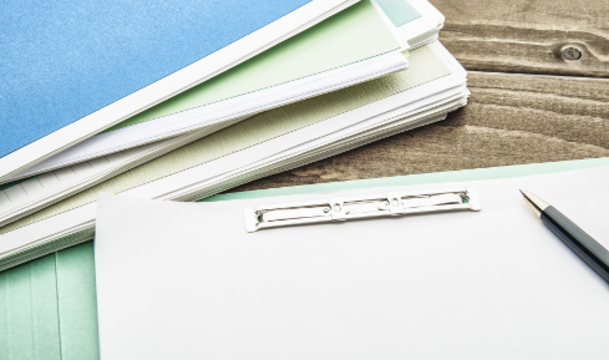 Unterlagen und Klemmbrett mit Stift auf einem Tisch