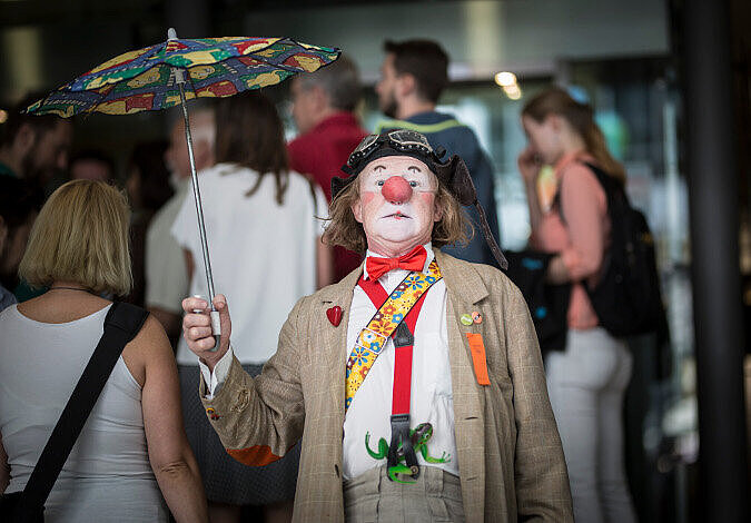 Foto: Portrait mit dem Clown, im Hintergrund stehen einige Besucher