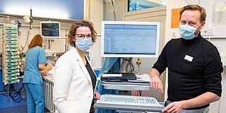Dr. Thomas Jack und Dr. Antje Wulff neben einem PDMS-Monitor auf der Kinderintensivstation