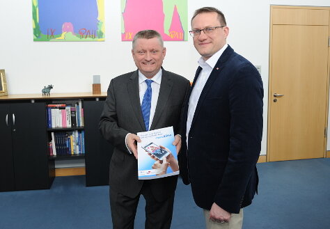 Foto: Bundesgesundheitsminister Hermann Gröhe steht neben Dr. med. Urs-Vito Albrecht und hält die Studie "Chancen und Risiken von Gesundheits-Apps" in die Kamera.
