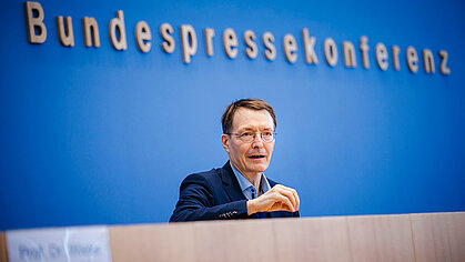 Bundesgesundheitsminister Prof. Karl Lauterbach spricht bei der Bundespressekonferenz. Hinter ihm ist der Schriftzug "Bundespressekonferenz" auf blauem Hintergrund zu sehen.