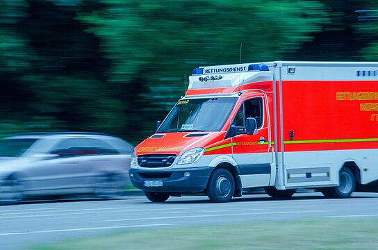 Foto: fahrender Rettungsdienst auf Straße überholt Auto