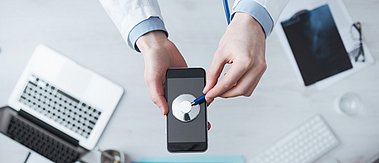 Stethoskop abgelegt auf Oberfläche eines Mobilfunkgeräts