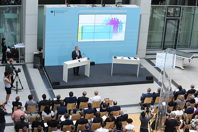 Foto (Vogelperspektive): Bundesgesundheitsminister Hermann Gröhe bei seiner Ansprache auf dem Podium im Foyer des Bundesgesundheitsministeriums