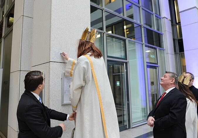 Ein Sternsinger schreibt den jährlichen Segen "C+M+B" an eine der Eingangssäulen des Ministeriums.