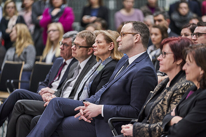 Foto der ersten Sitzreihe mit den Staatssekretären, der Drogenbeauftragten und Jens Spahn, im Hintergrund weitere Zuschauer