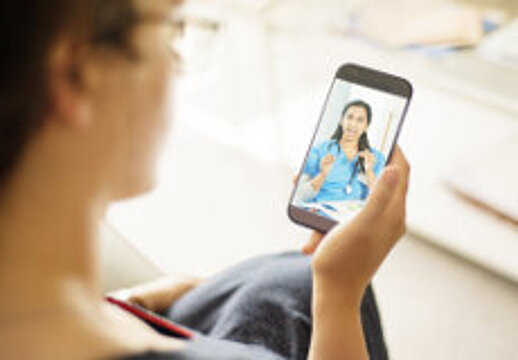 Ein Patient spricht mit einer Ärztin per Videotelefonie über ein Smartphone.