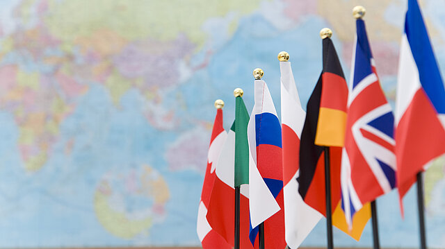 Bild: G7-Flaggen vor Weltkarte.