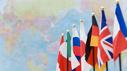 Bild: G7-Flaggen vor Weltkarte.