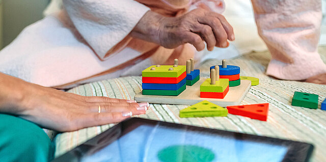 Ärztin und Patienten beim geometrischen Formen Spiel: Transfer evidenzbasierter Präventions- und Versorgungskonzepte in die Routineversorgung von Menschen mit Demenz stärken