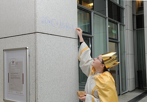 Foto: Ein Mädchen schreibt an eine Säule im Atrium den Segen der Sternsinger