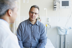 Ein Arzt spricht mit einem männlichen Patient im Krankenhauszimmer