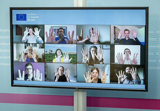 Screenshot bei der Konferenz zur Zukunft Europas. Die zwölf Teilnehmenden im Bild halten die Hände in die Kamera und signalisieren mit den Fingern die Zahlen von 7, 8 und 9.