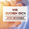 Eine Hand hält eine Karte hoch mit der Aufschrift: "Wir suchen dich - jetzt bewerben"
