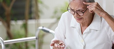Senior schaut auf Tabletten in seiner Hand