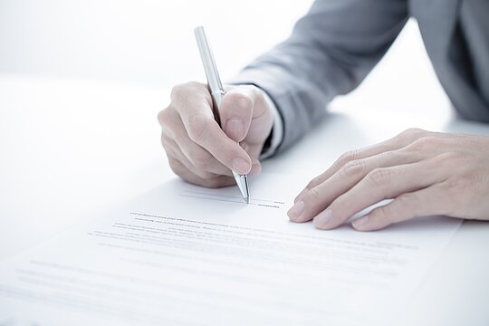 Foto: Eine Person schreibt mit einem Stift etwas auf Papier