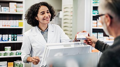 Apothekerin übergibt Kunden sein Medikament