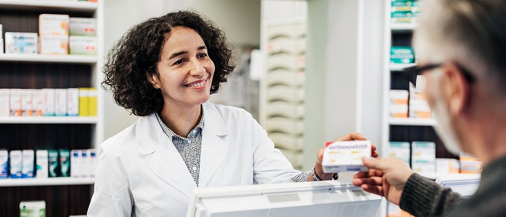 Apothekerin übergibt Kunden sein Medikament